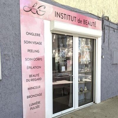 Enseigne rose de l’institut LC Onglerie Beauté, affichant les prestations sur une façade grise, avec vitrine et logo visible en haut à gauche.
