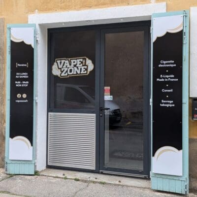 Panneaux signalétiques pour la boutique Vape Zone Façade de la boutique Vape Zone avec vitrophanie noire et dorée, affichant le logo, les horaires et les services proposés.