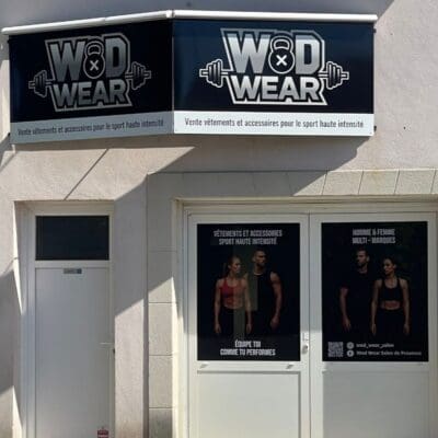 Façade de boutique avec enseigne "WOD WEAR" et affiches de vêtements de sport haute intensité.