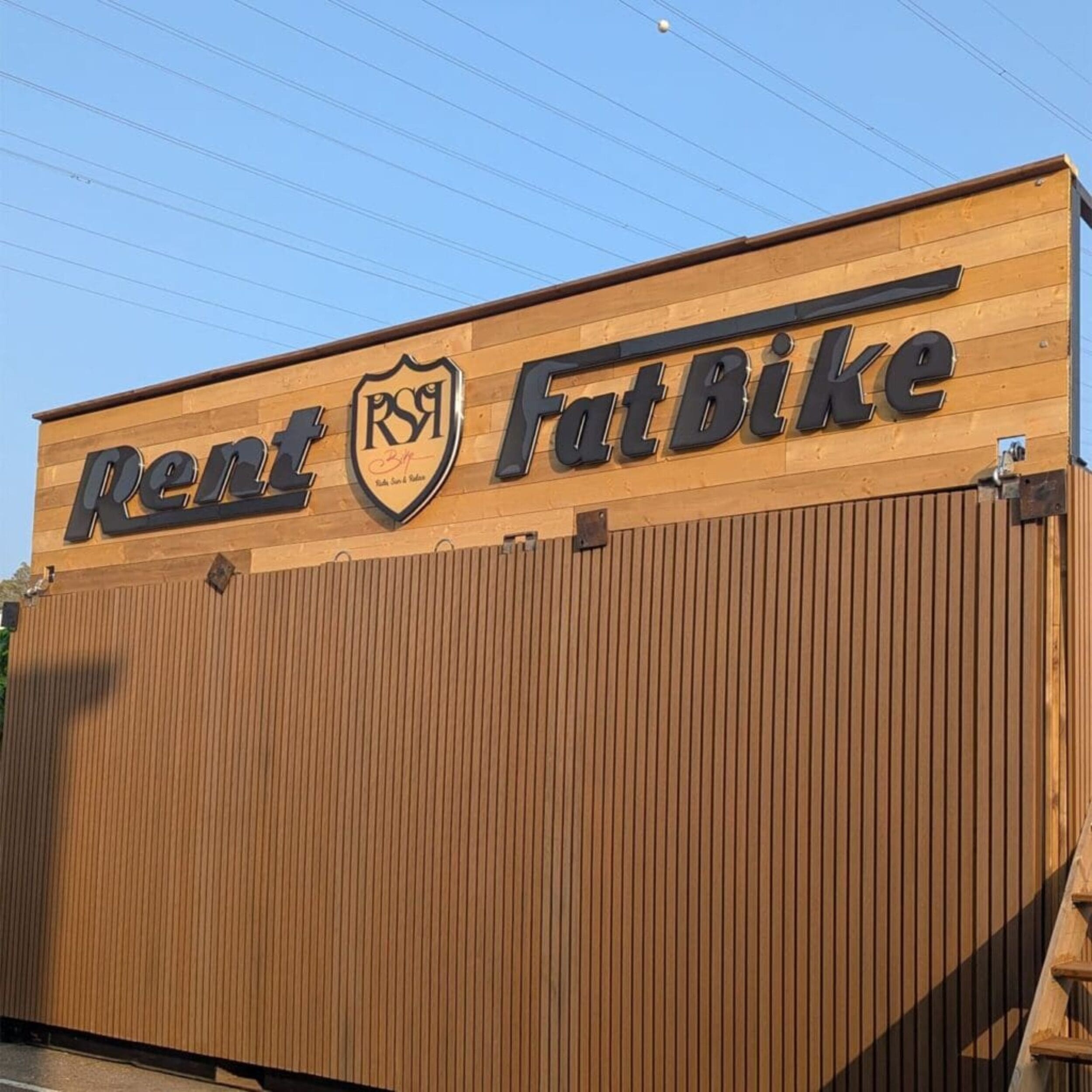 Façade en bois avec l'inscription "Rent FatBike" et le logo central "RSR".